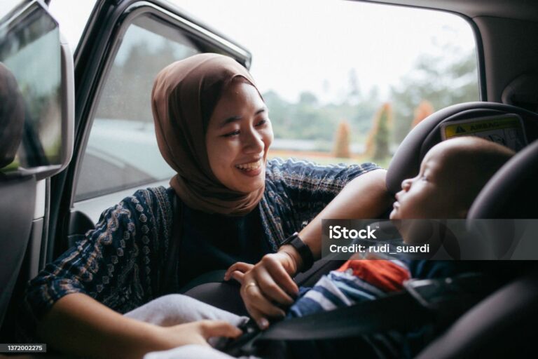 asian muslim woman fastening her baby seat