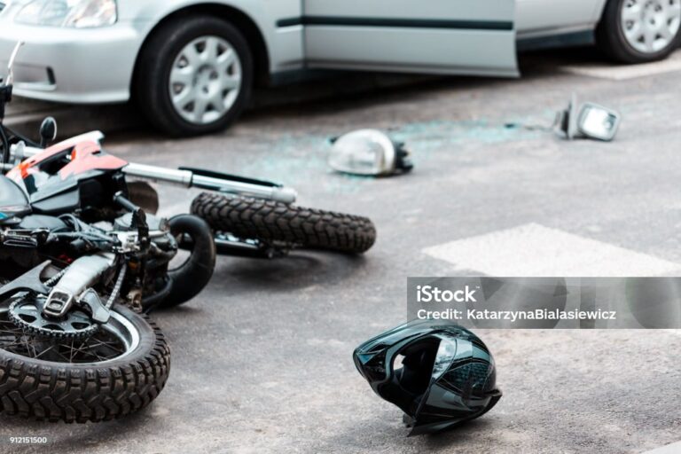 Overturned motorcycle and helmet on the street after collision with the car