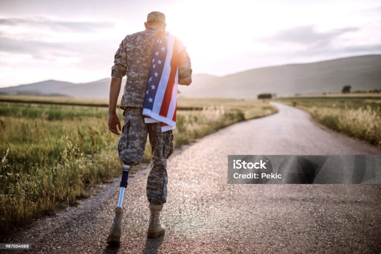 Rear View Of Young Amputee Soldier Walking Road Wearing American Flag